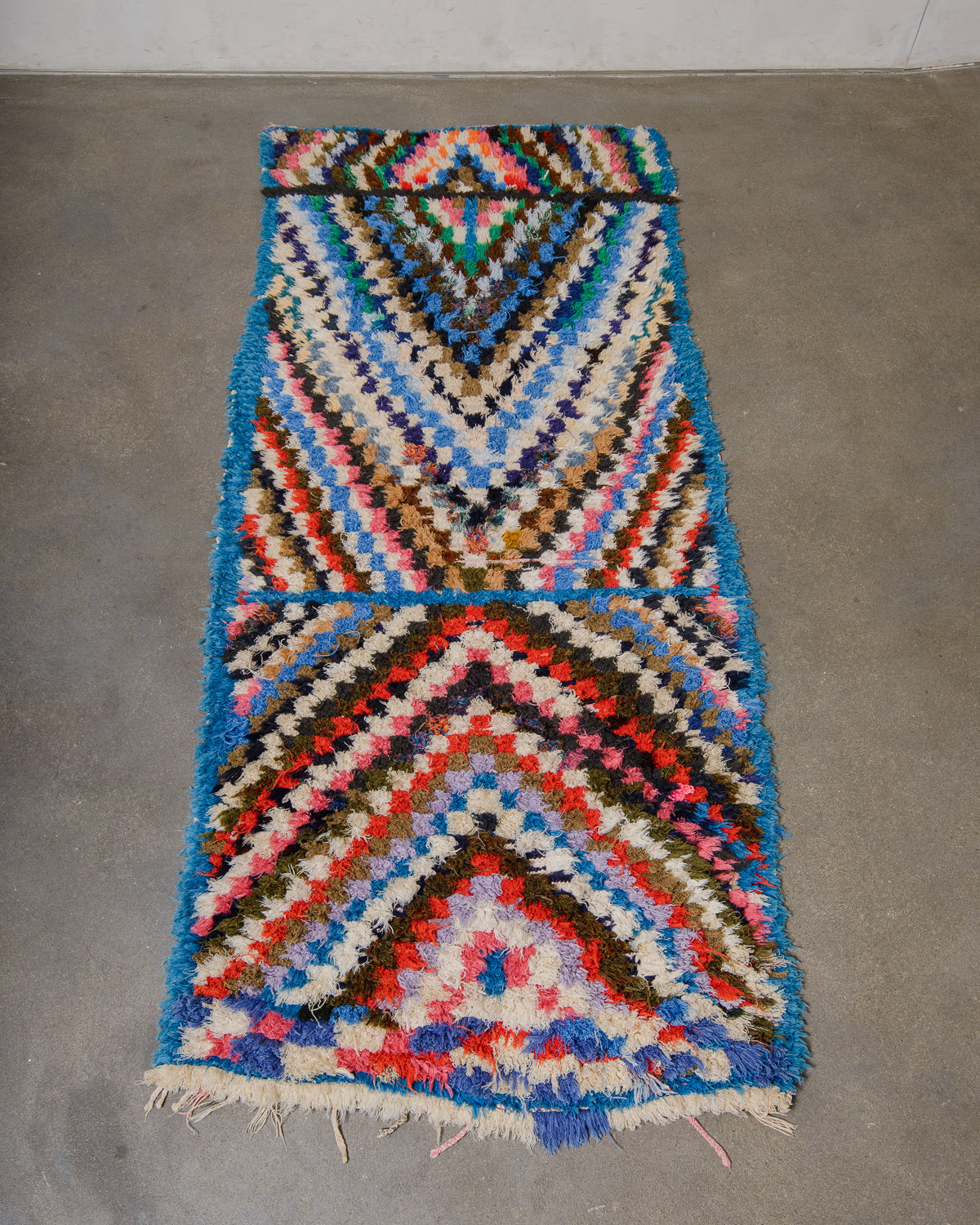Berberlin vintage Boucherouite runner rug laying flat on concrete floor.